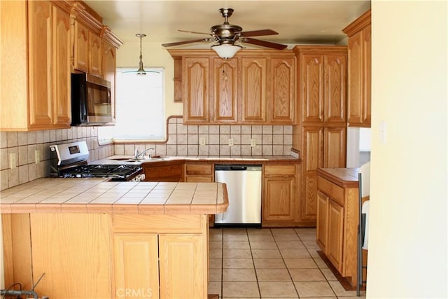 kitchen featuring pendant lighting, decorative backsplash, appliances with stainless steel finishes, tile counters, and light tile patterned floors