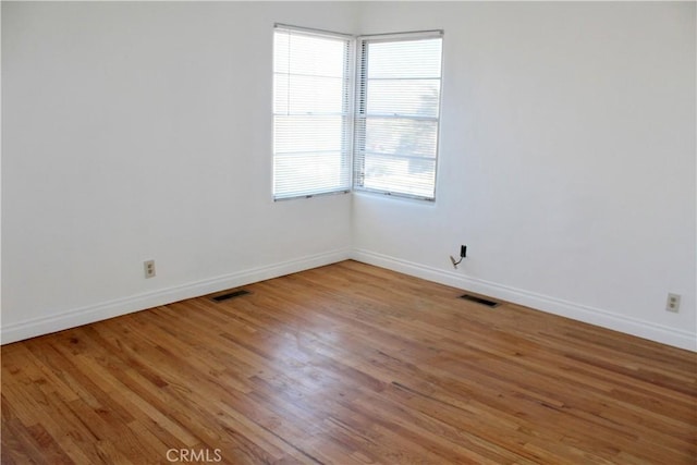 spare room featuring a healthy amount of sunlight and wood-type flooring