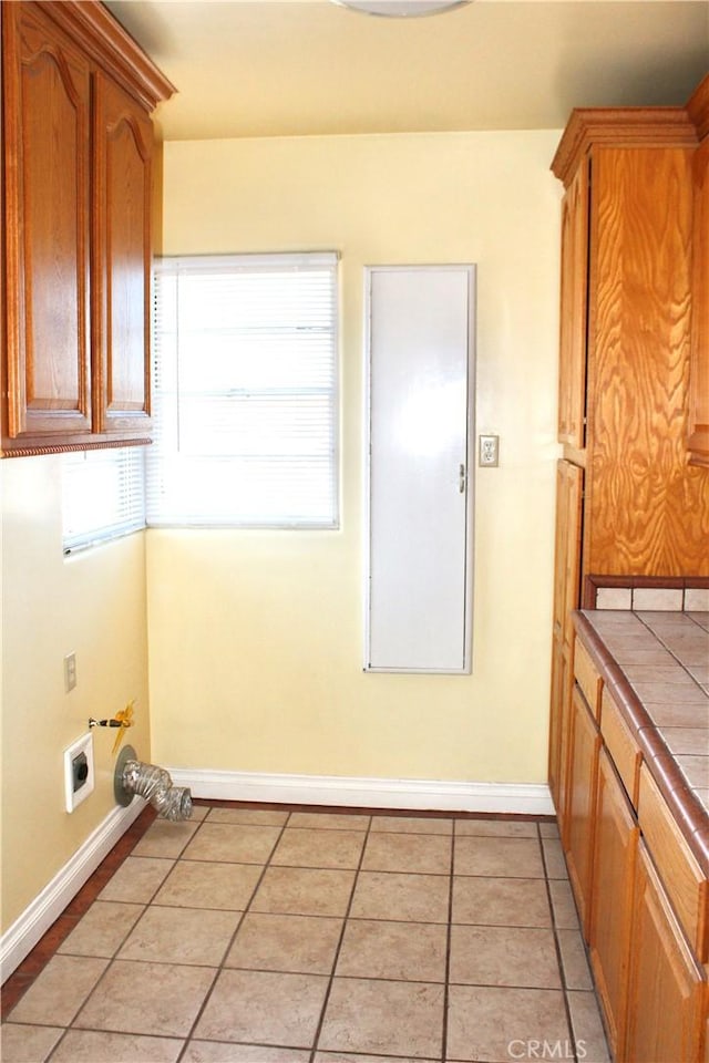 washroom featuring light tile patterned flooring, hookup for a washing machine, electric dryer hookup, and cabinets