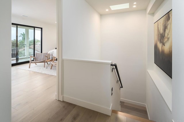 hallway with a skylight and light hardwood / wood-style floors