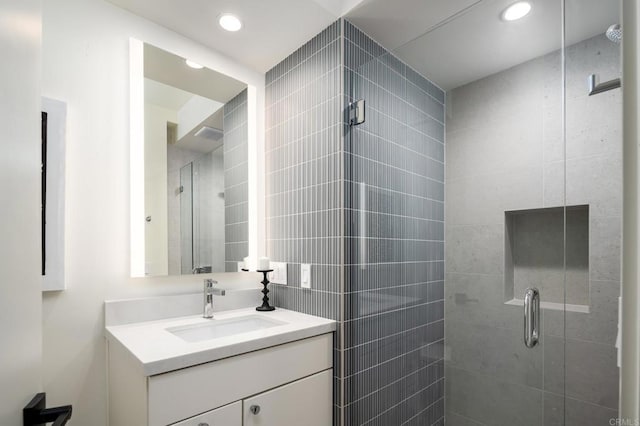 bathroom featuring a shower with shower door and vanity