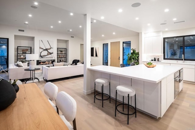 kitchen featuring backsplash, a spacious island, sink, white cabinetry, and a kitchen breakfast bar