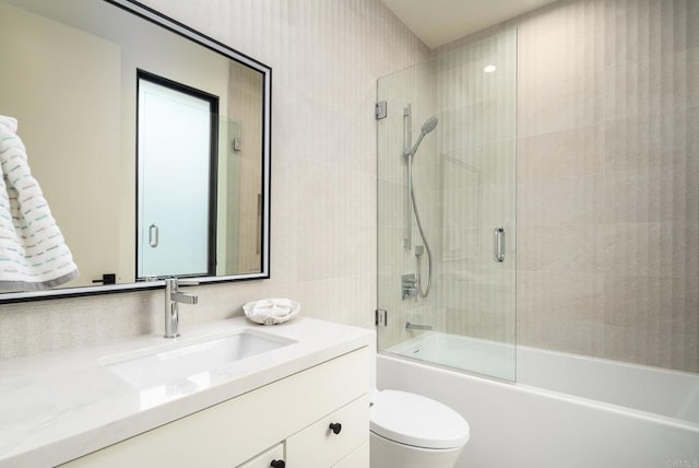 full bathroom featuring toilet, bath / shower combo with glass door, and vanity