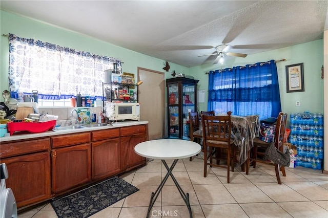 dining room featuring ceiling fan, sink, a textured ceiling, and light tile patterned flooring