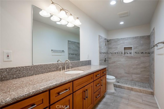 bathroom featuring toilet, vanity, and a tile shower