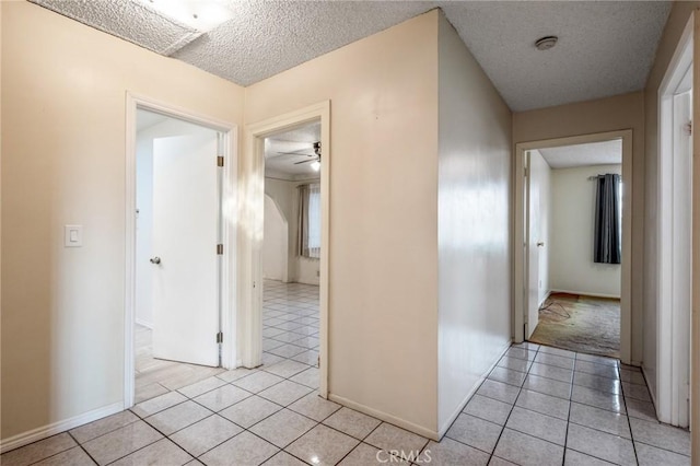 hall with light tile patterned floors and a textured ceiling