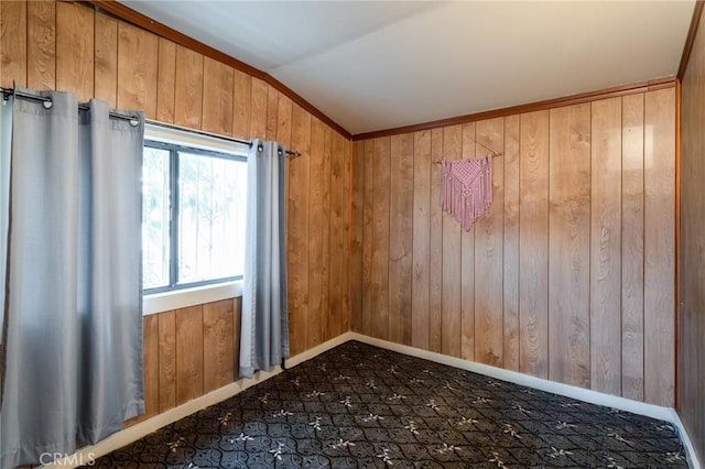 spare room with crown molding, lofted ceiling, and wooden walls