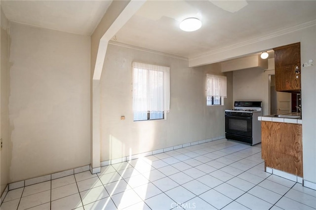 kitchen featuring tile counters, light tile patterned floors, white gas stove, and ornamental molding