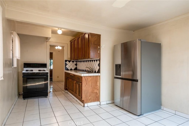 kitchen with tasteful backsplash, ornamental molding, light tile patterned floors, stainless steel fridge, and range with gas stovetop