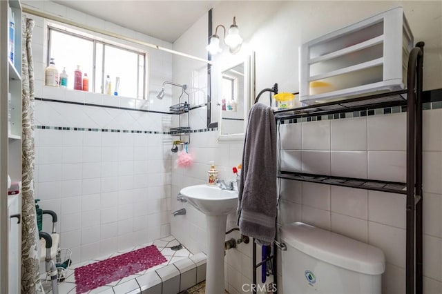 bathroom with toilet, tile walls, and a tile shower