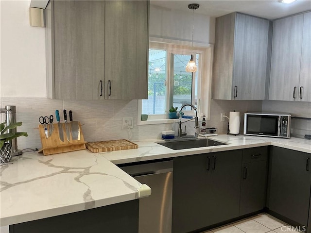 kitchen with sink, light stone counters, hanging light fixtures, gray cabinets, and stainless steel appliances