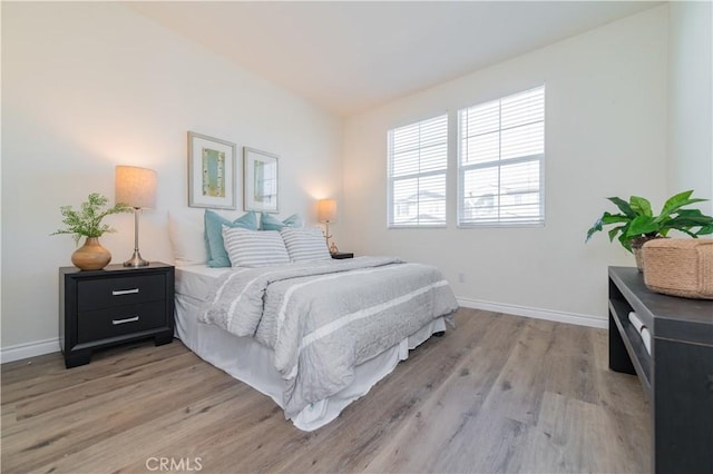 bedroom with vaulted ceiling and light hardwood / wood-style flooring