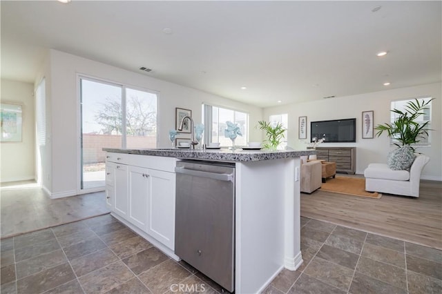 kitchen featuring white cabinets, stainless steel dishwasher, a center island with sink, and sink