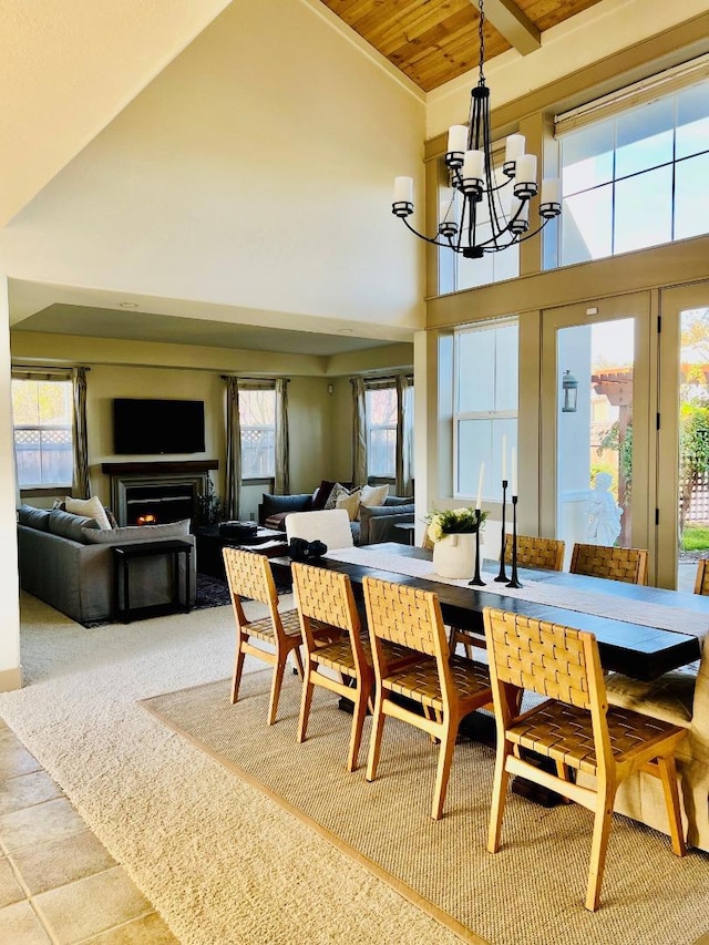 dining space with a notable chandelier, wooden ceiling, plenty of natural light, and high vaulted ceiling