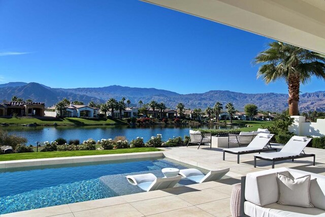 view of swimming pool with a water and mountain view and a patio