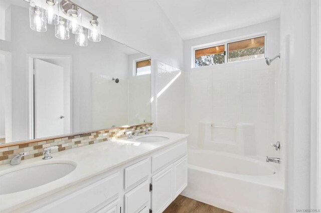 bathroom with lofted ceiling, hardwood / wood-style floors, backsplash, shower / bathing tub combination, and vanity