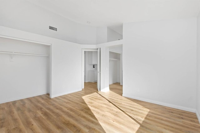 unfurnished bedroom with a high ceiling, a closet, and hardwood / wood-style flooring