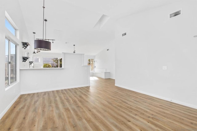 unfurnished living room featuring a high ceiling and light hardwood / wood-style floors