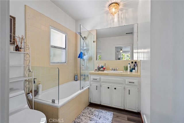 full bathroom with toilet, vanity, tasteful backsplash, tiled shower / bath, and hardwood / wood-style flooring