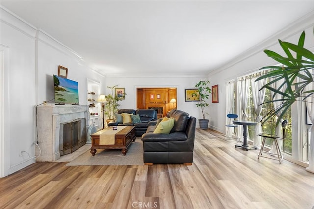 living room featuring a fireplace, crown molding, and light hardwood / wood-style floors