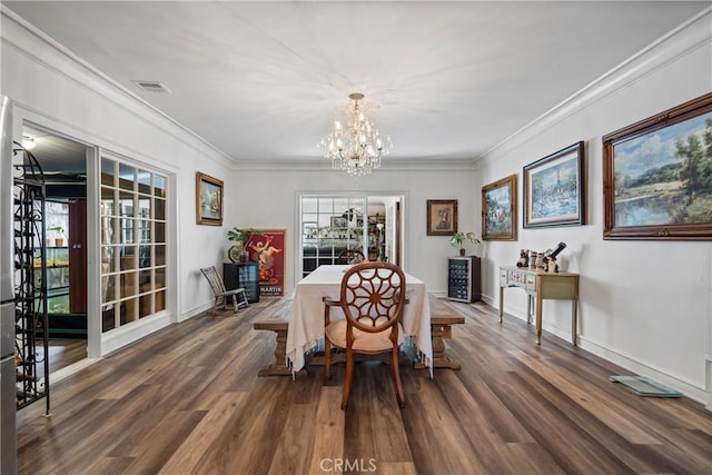 dining area featuring dark wood-type flooring, crown molding, and an inviting chandelier