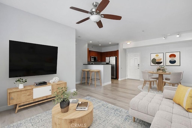 living room featuring ceiling fan and light wood-type flooring