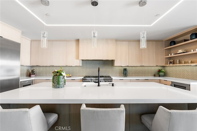 kitchen featuring decorative light fixtures, decorative backsplash, stainless steel fridge, and a center island with sink