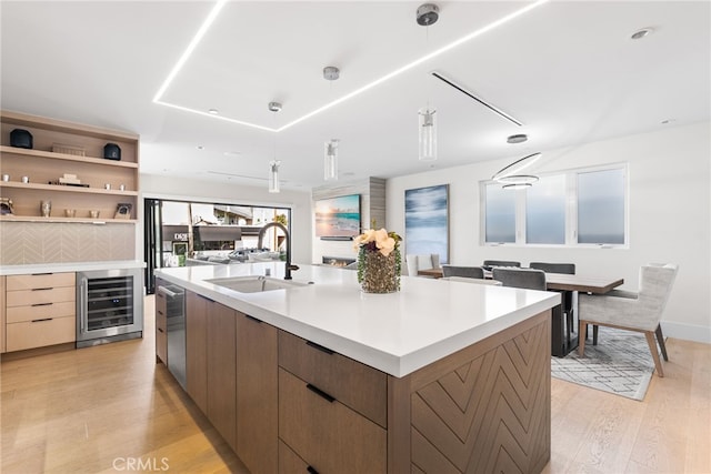 kitchen with light wood-type flooring, sink, beverage cooler, and a spacious island