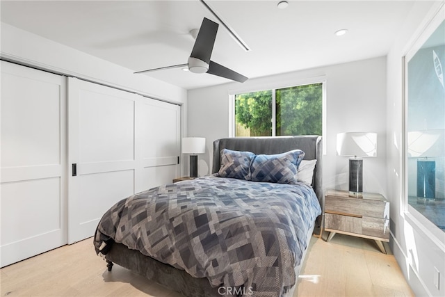 bedroom with ceiling fan, a closet, and light hardwood / wood-style floors