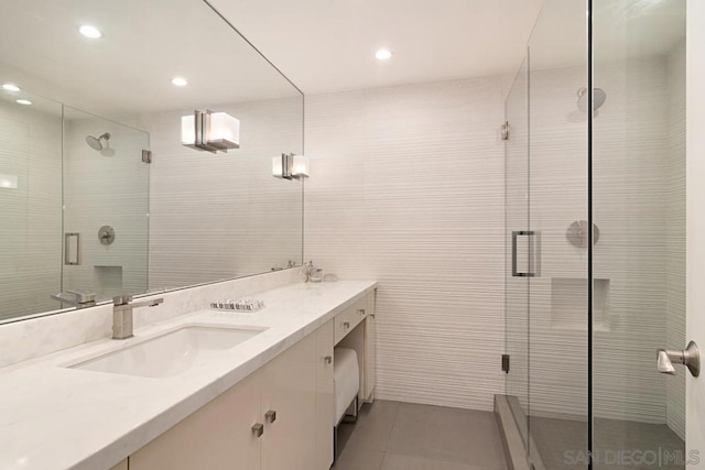 bathroom with vanity, tile patterned flooring, tile walls, and walk in shower