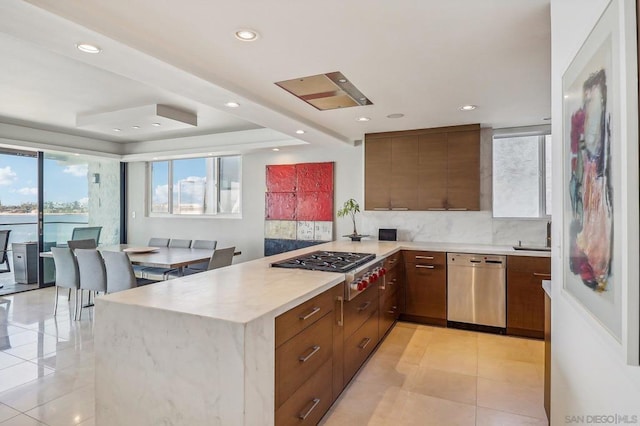 kitchen with light tile patterned floors, stainless steel appliances, and kitchen peninsula