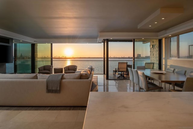 tiled living room featuring a water view, a wall of windows, and a wealth of natural light