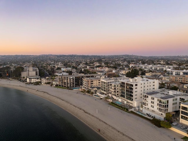 aerial view at dusk with a water view and a view of the beach