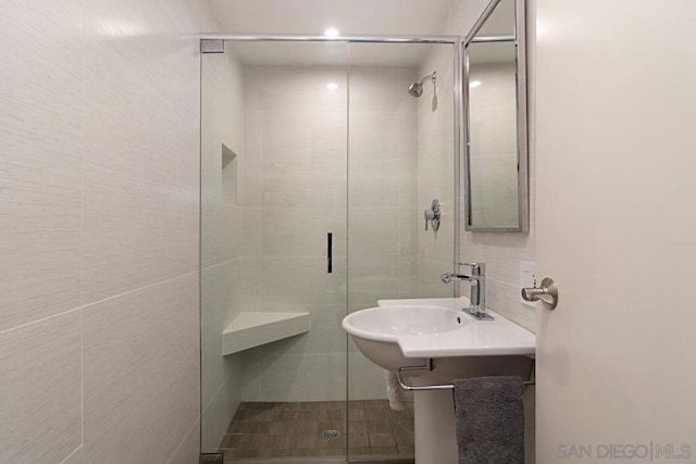 bathroom with sink, tile walls, and walk in shower