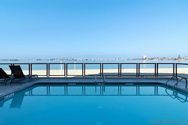 view of swimming pool featuring a water view and a view of the beach