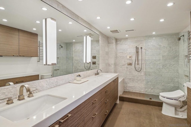 bathroom with toilet, vanity, and a tile shower