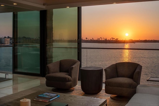 living room with tile patterned floors, a wall of windows, and a water view