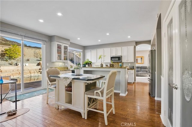 kitchen with a kitchen island, a breakfast bar area, white cabinets, hardwood / wood-style flooring, and stainless steel appliances