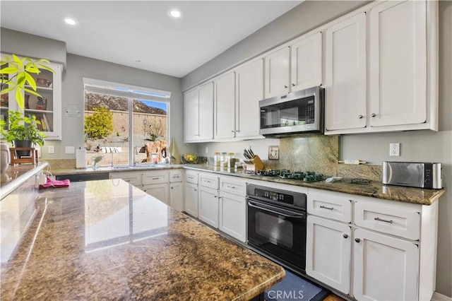 kitchen featuring tasteful backsplash, appliances with stainless steel finishes, white cabinets, and dark stone counters