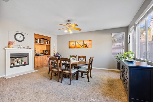 dining area featuring built in shelves, light colored carpet, and ceiling fan