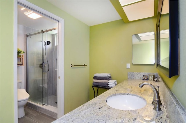 bathroom featuring a shower with shower door, toilet, and vanity