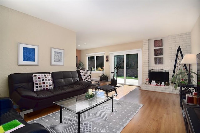 living room with a brick fireplace and hardwood / wood-style floors