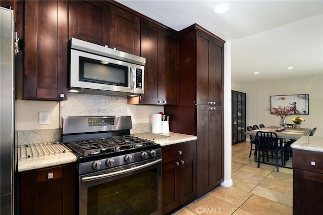 kitchen with light tile patterned floors, stainless steel appliances, and light stone counters