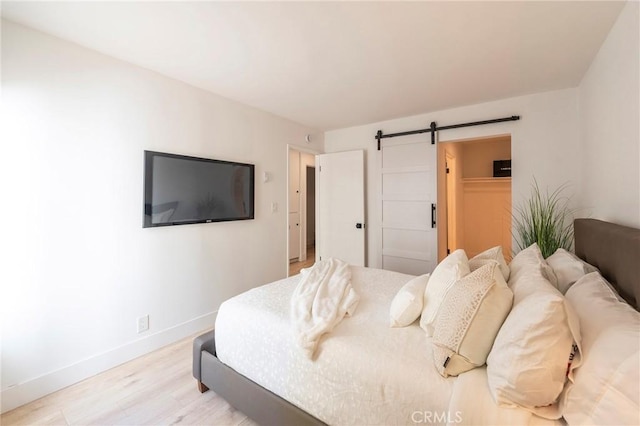 bedroom with a barn door, a closet, and light hardwood / wood-style flooring