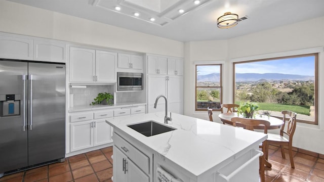 kitchen with a center island with sink, sink, a mountain view, appliances with stainless steel finishes, and white cabinets