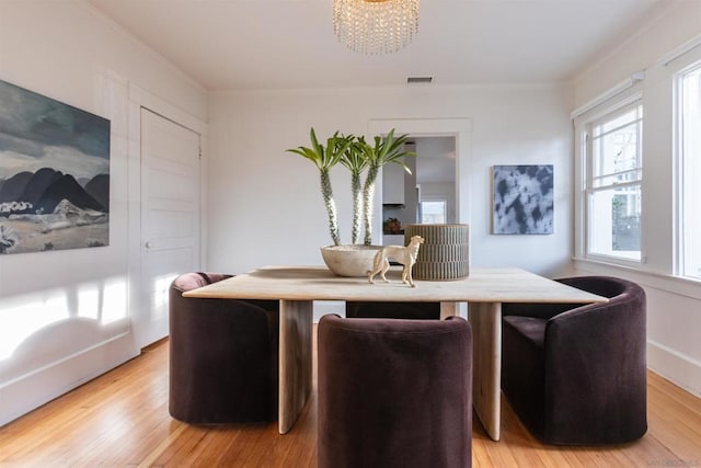 dining room with light hardwood / wood-style flooring, crown molding, and an inviting chandelier