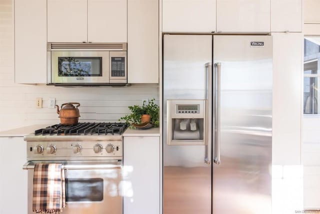 kitchen featuring white cabinets, premium appliances, and tasteful backsplash