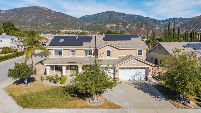 view of front of house featuring a garage, a mountain view, a front yard, and solar panels