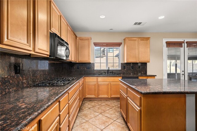 kitchen featuring light tile patterned flooring, stainless steel gas stovetop, sink, and dark stone countertops