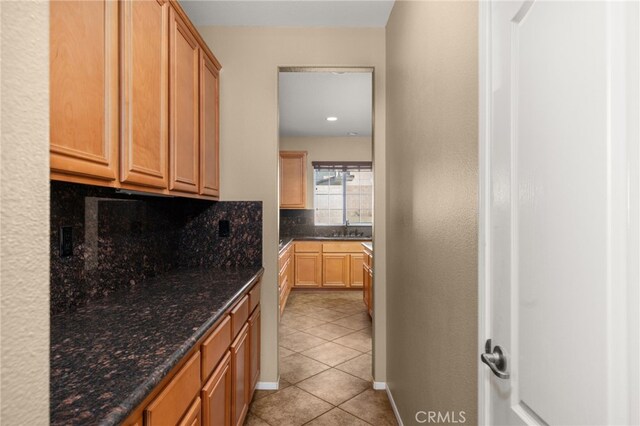 kitchen with tasteful backsplash, sink, dark stone countertops, and light tile patterned floors